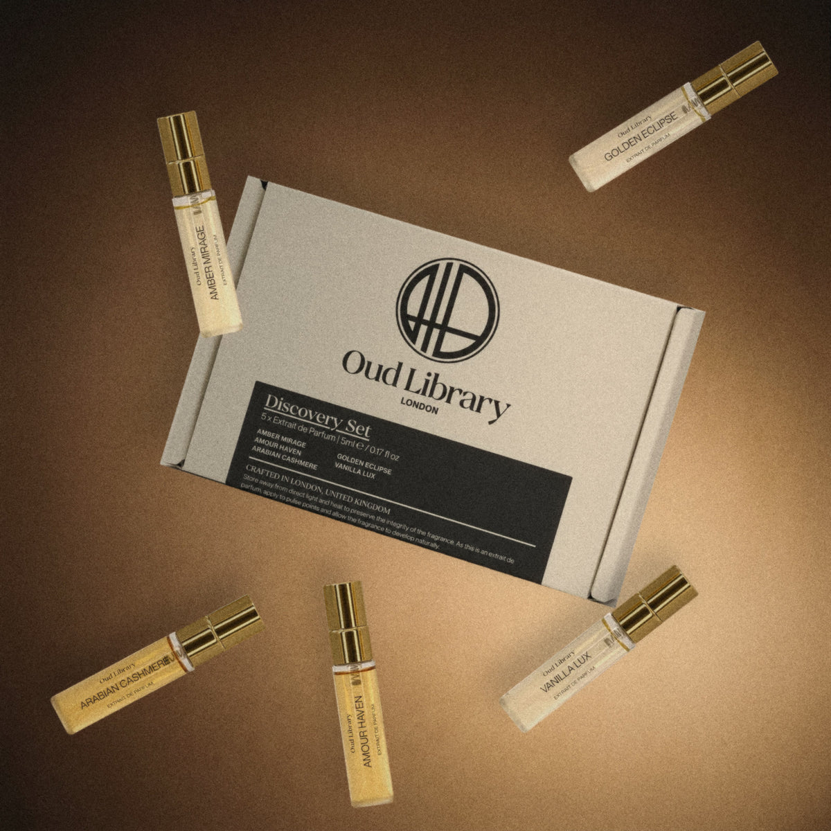 The Oud Library Extrait de Parfum Discovery Set box with its five 5ml sprays floating around it in warm light