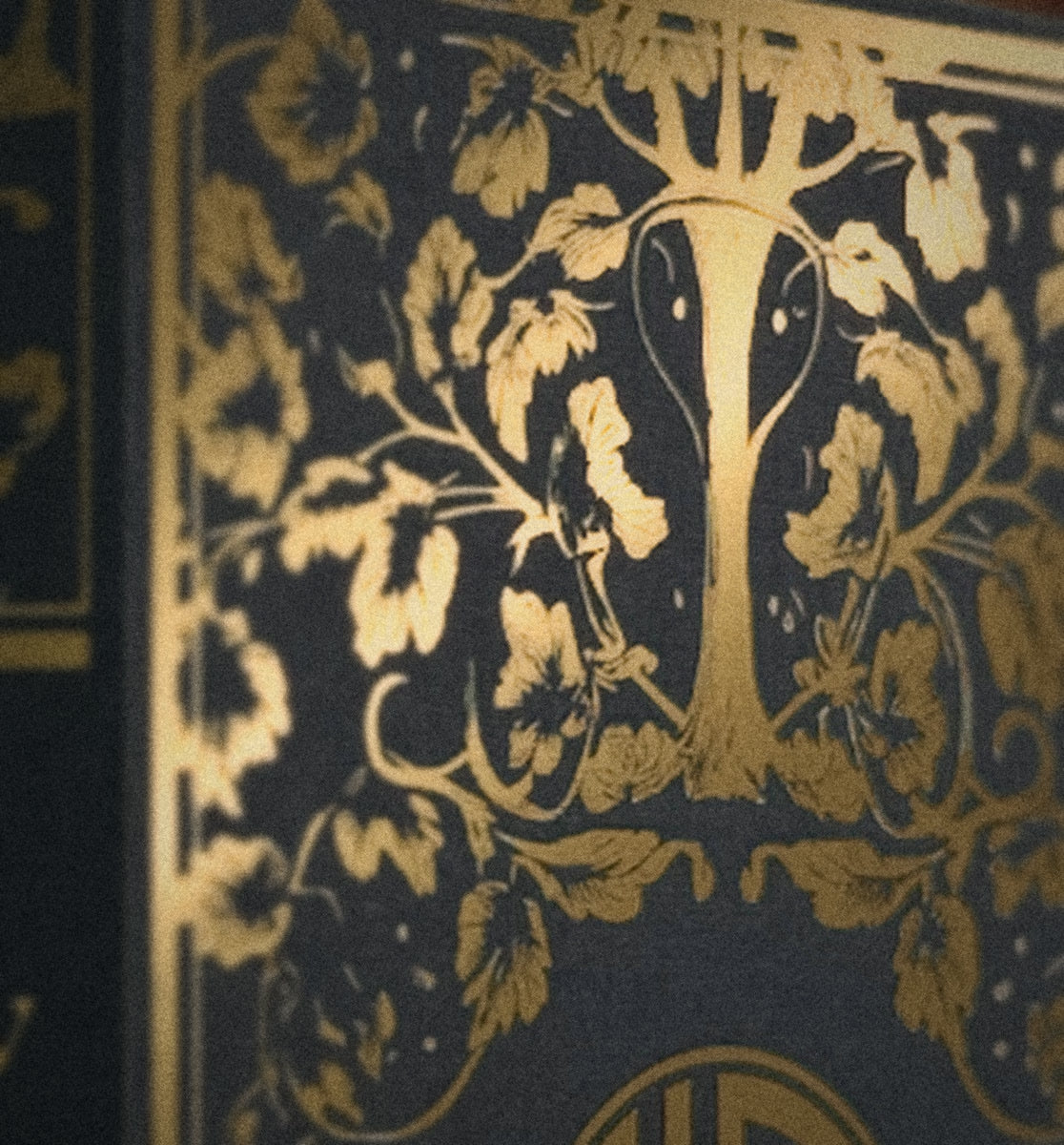 Macro of the gold foil tree on the Oud Library 20ml Parfum Oil box, in warm lamp light
